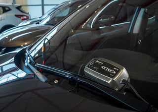 Car with a CTEK MXS 10 device attached to the windshield in a showroom setting